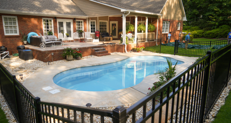 pool with black iron rod fence and river rock around